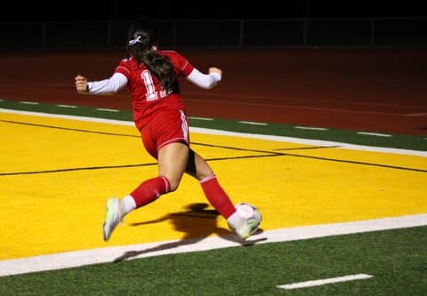 Girls soccer player with right leg cocked back, about to kick the ball