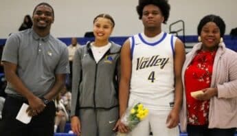 A black man, black teen girl, black teen boy and black woman. The boy and girl are holding hands and a bouquet of flowers. Both are athletes. He is in a basketball uniform.