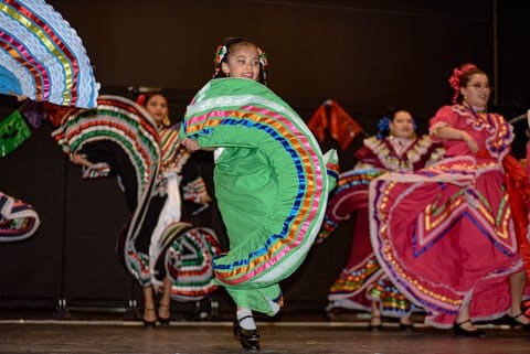 Dancers on stage in colorful Mexican dresses with big skirts