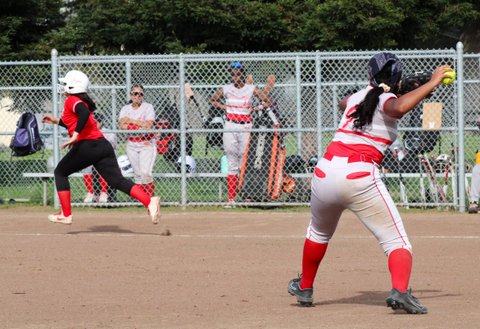 Softball player prepares to throw the ball with opponent running