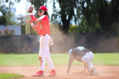 Infielder stands with glove closed and an opponent on the ground and a cloud of dirt behind him