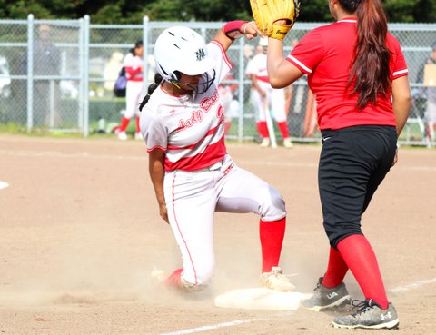 Softball player sliding into third in front of defender
