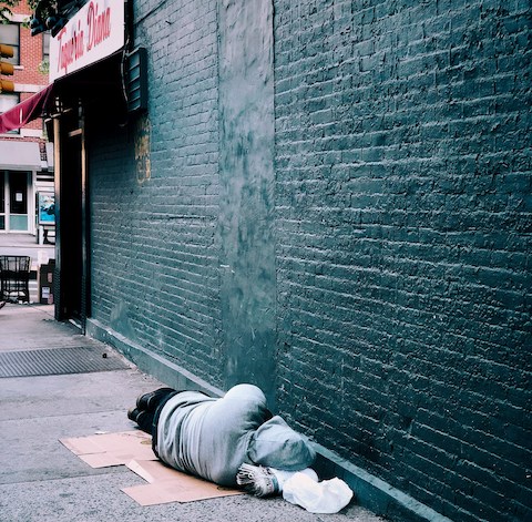 person sleeping on cardboard on sidewalk