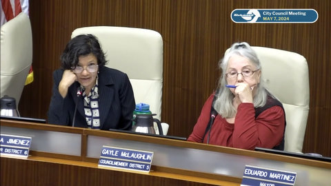 A middle-aged Latina woman and older white woman in government meeting