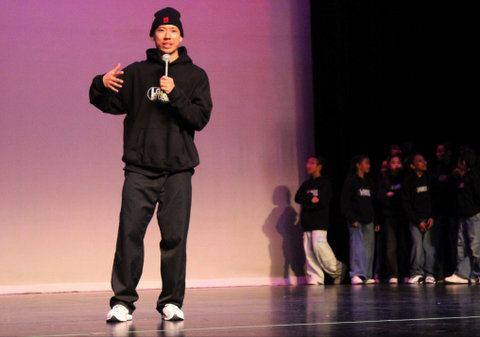 a young asian man holding a microphone and wearing black beanie, hoodie and pants