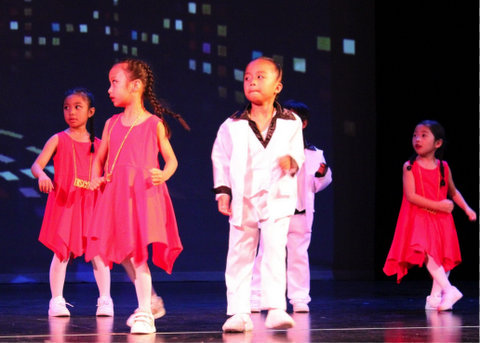 Small children wearing either a red dress or white suit with black trim like characters from saturday night fever