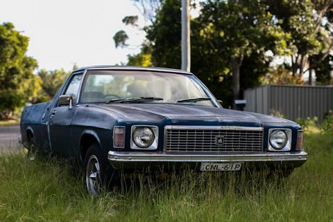 an older-looking dark gray muscle car parked on grass