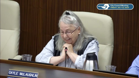 an older white woman with gray hair, looking down with hands clasped and happy expression. nameplate says gayle McLaughlin. onscreen text says richmond city council friday july 12 2024