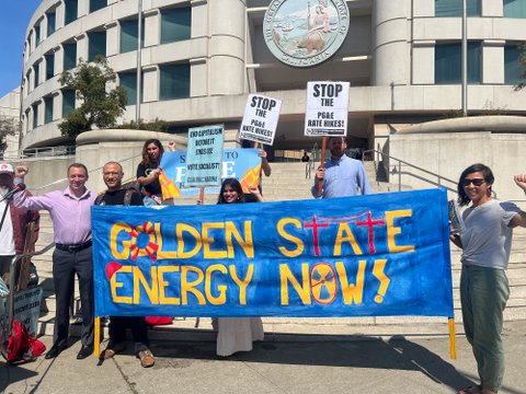 people standing with banner that says golden state energy now and signs that say stop the PG&E rate hikes and end capitalism before it ends us vote socialist. They are outside a building with the california state logo