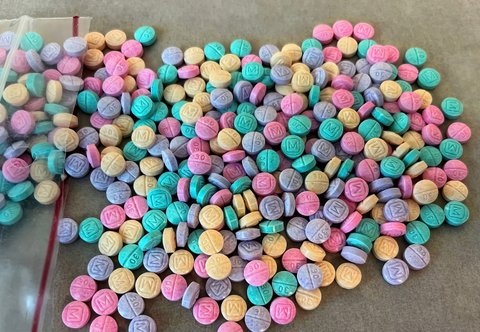 a bunch of brightly colored round tablet pills in pink, purple, yellow and green