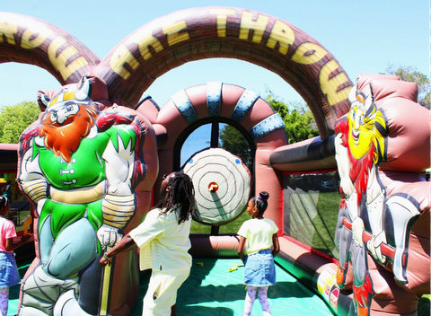 a black man and girl stand at an archway that says axe throw with a bullseye at the end and a viking-like figure at the front