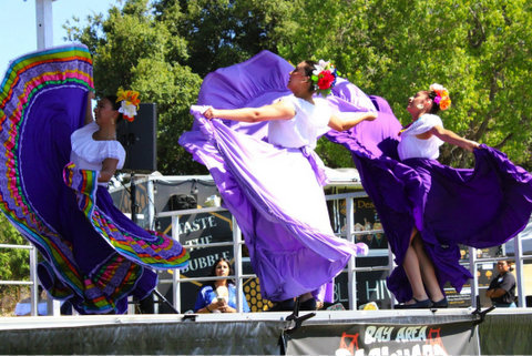 three latina folklorico dancers spinning their purple skirts