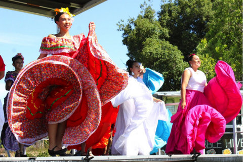 three latina folklorico dancers moving their skirts with a flourish