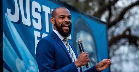 black man in a blue suit speaking with a microphone