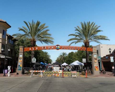 archway that says old town pittsburg over a street with two palm trees rising above it and a road closed sign and barriers in front of it