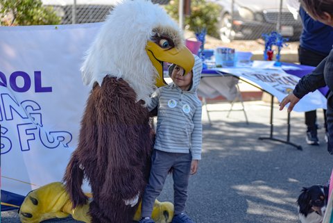 person in an eagle costume and a little boy. the boy's face is visible through the eagle's open beak