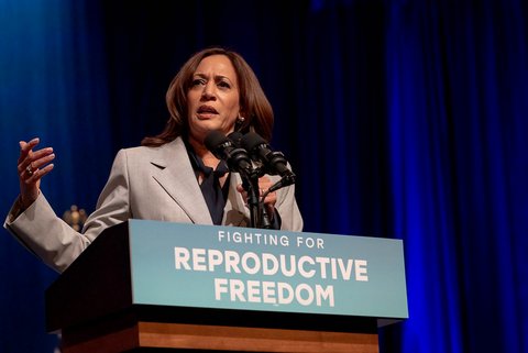 kamala harris, a black and south asian woman, speaking at a lectern adorned with a sign that reads fighting for reproductive freedom