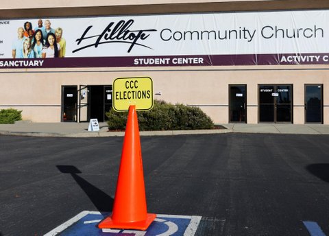 orange cone in a handicapped parking spot with a yellow sign that reads CCC elections in front of a building with a sign that reads hilltop community church