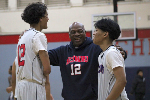 a black man in a Richmond number 12 hoodie standing between two high school basketball players