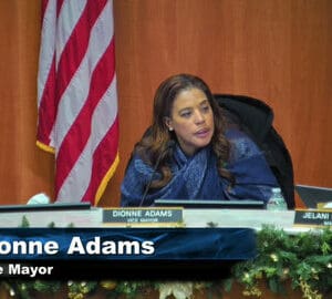 a black woman with onscreen text that says dionne adams vice mayor and US flag behind her