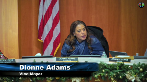 a black woman with onscreen text that says dionne adams vice mayor and US flag behind her