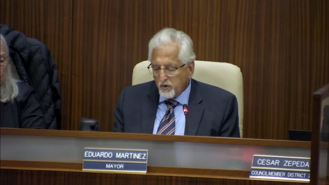 latino man with white hair and goatee with nameplate that says eduardo martinez mayor