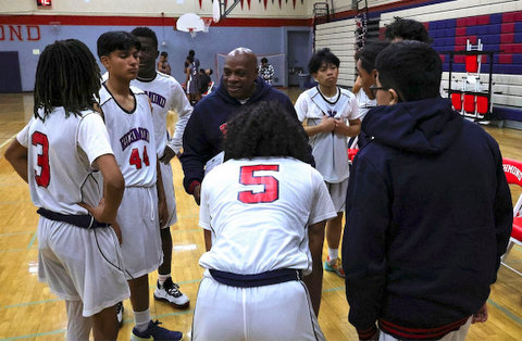 high school basketball players and their coach gathered on the sidelines