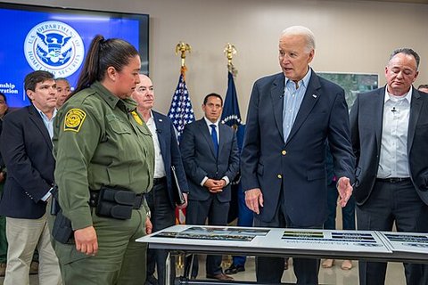 president biden and a woman in a border patrol uniform in a room with other men in suits