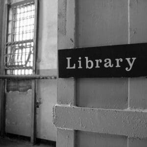 black and white photo showing a library sign near a barred window