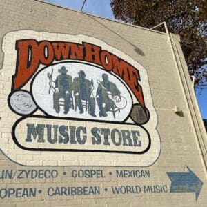 "Down Home music store cajun zydeco gospel mexican european caribbean world music" painted on beige brick wall with illustration of three seated musicians