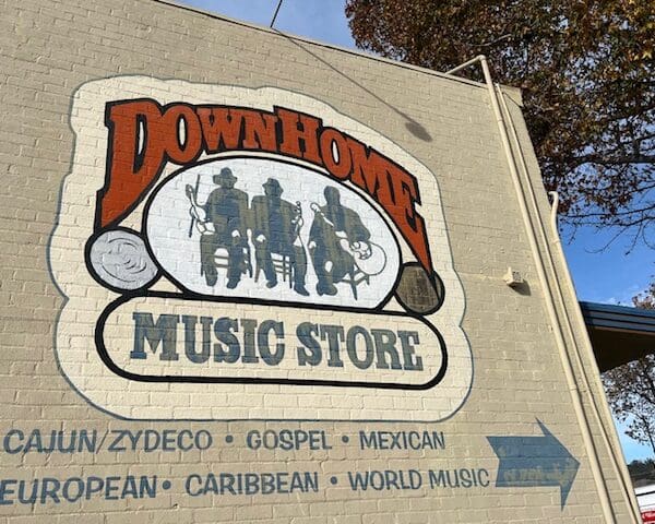 "Down Home music store cajun zydeco gospel mexican european caribbean world music" painted on beige brick wall with illustration of three seated musicians