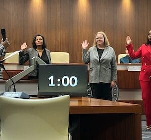 a latina woman, white woman and black woman being sworn into a city council by a black woman