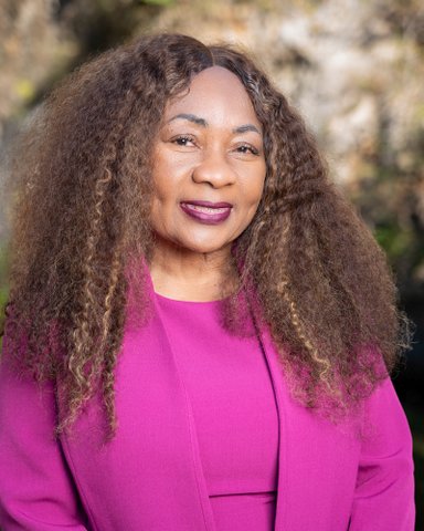 a black woman with long curly hair wearing a fuschia jacket and top