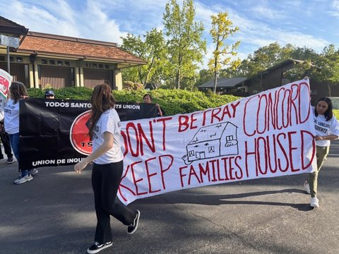 people carrying banner in street that reads don't betray concord keep families housed