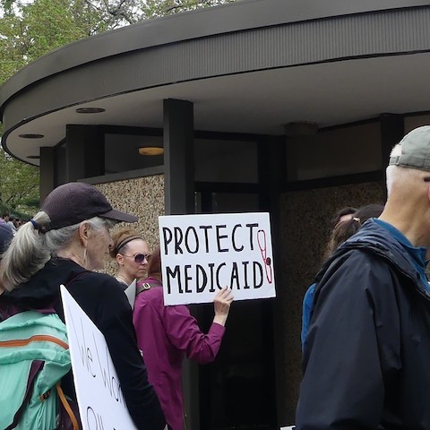 person in crowd holding sign that reads protect medicaid