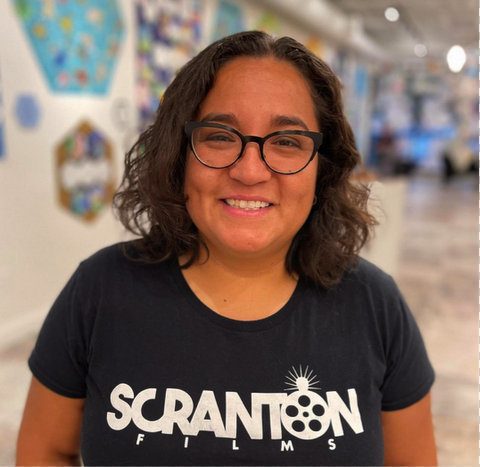 smiling latina woman wearing glasses and T shirt that says scranton films