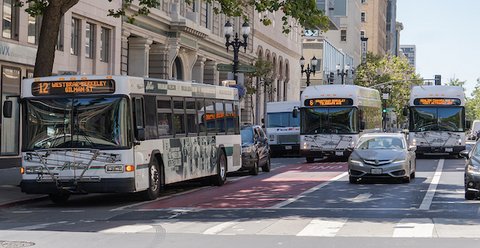traffic on a city street including three AC transit buses in different lanes and at different distances away