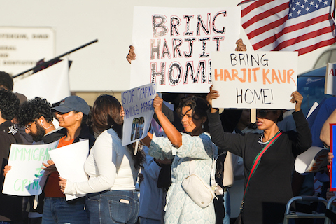 a crowd of demonstrators with signs including ones that say bring harjit home and bring harjit kaur home. a US flag flies behind them
