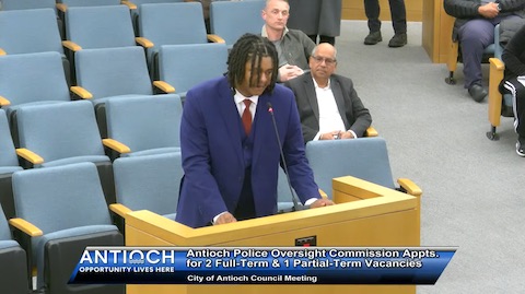 young black man in a blue suit with red tie standing at a lectern. onscreen text reads antioch opportunity lives here, antioch police oversight commission appointments for 2 full term and 1 partial term vacancies, city of antioch council meeting