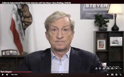 screenshot of Tom Steyer, an older white man in a suit with no tie, in you tube video. a california flag and sign that says steyer for governor are behind him. on screen text reads california gubernatorial race series interview with tom steyer, news briefing, 5/26/26